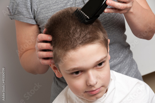 haircut of a blond boy using a hair clipper