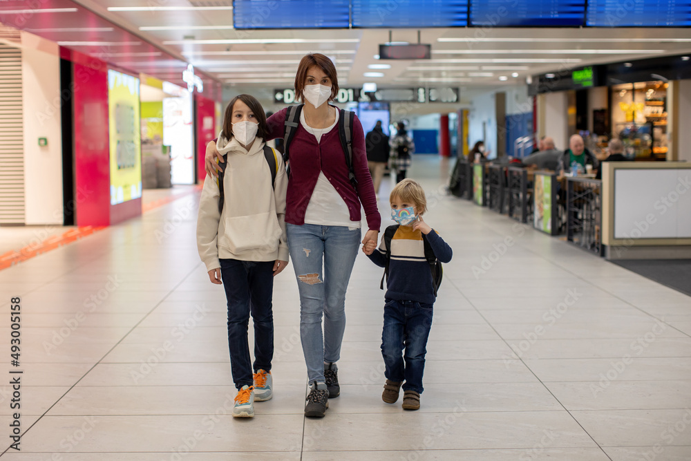 Fototapeta premium Cute baby boy waiting boarding to flight in airport transit hall near departure gate. Active family lifestyle travel by air with children