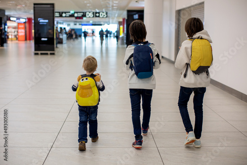 Cute baby boy waiting boarding to flight in airport transit hall near departure gate. Active family lifestyle travel by air with children