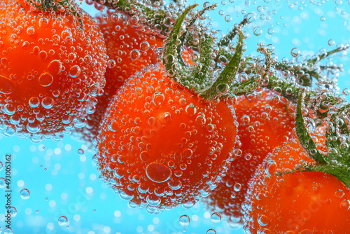 Red tomato close-up under water. Juicy vegetable with a bubble on blue background. © Алексей Филатов
