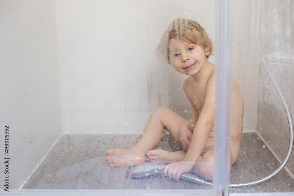 Blond child, sweet toddler boy in bathroom, taking shower, sitting on the floor, punished - obrazy, fototapety, plakaty 