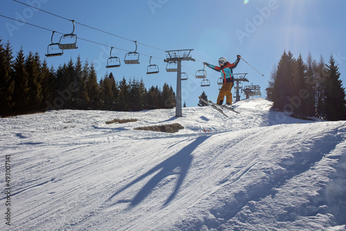 Happy preteen child, jumping with ski in a snow fun park. Kid skiing in Italy on a sunny day, kids and adults skiing together
