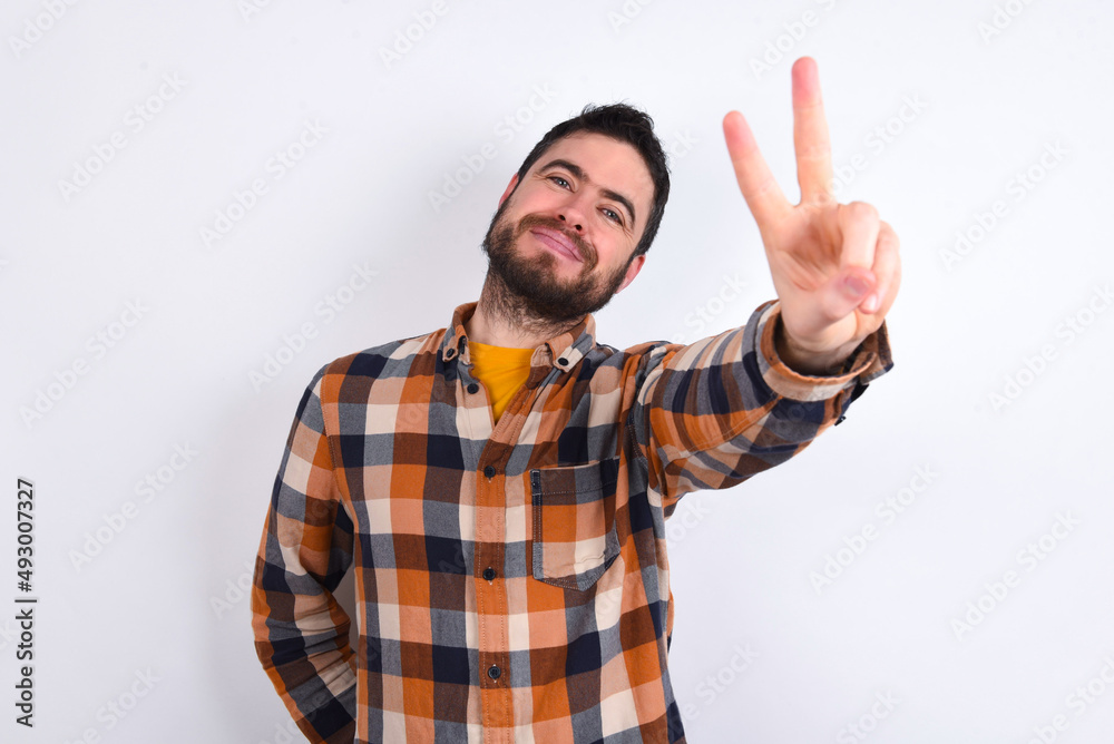 young caucasian man wearing plaid shirt over white background directs fingers at camera selects someone. I recommend you. Best choice