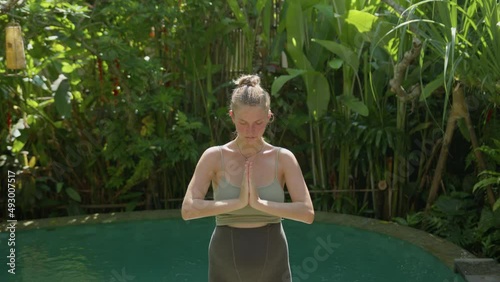 Pregnant woman do yoga poses at home with garden on the background and embrace her belly. Sunshine summer vibes