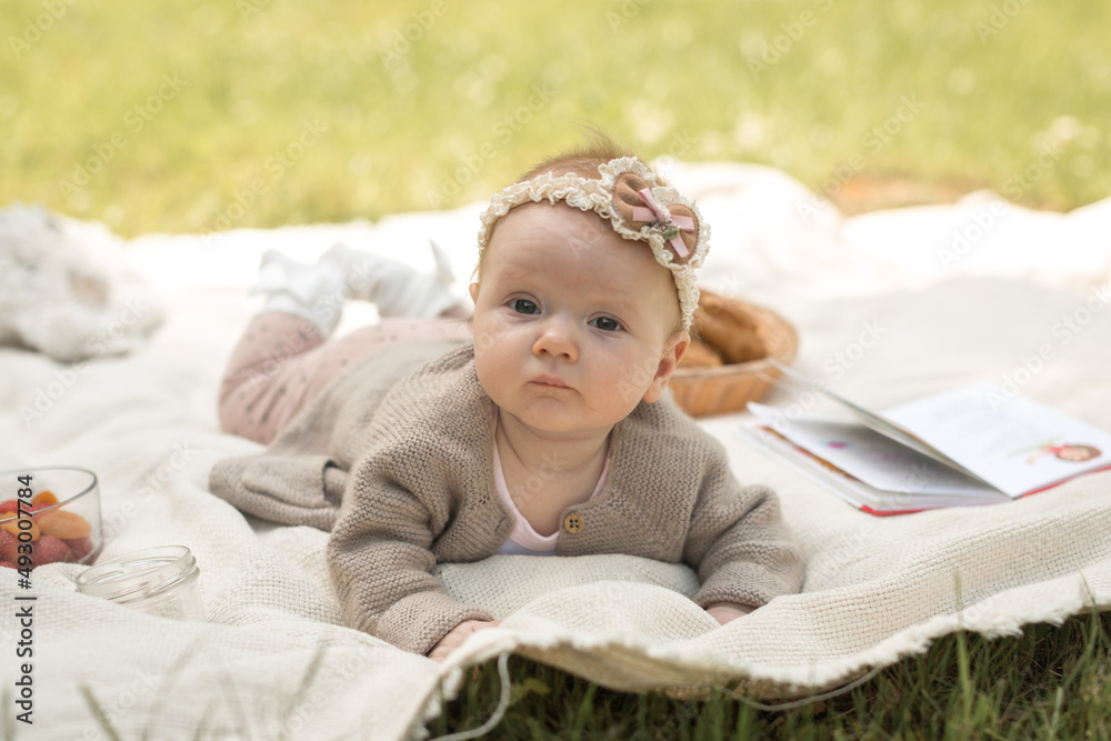 little girl lies on a blanket at a summer picnic