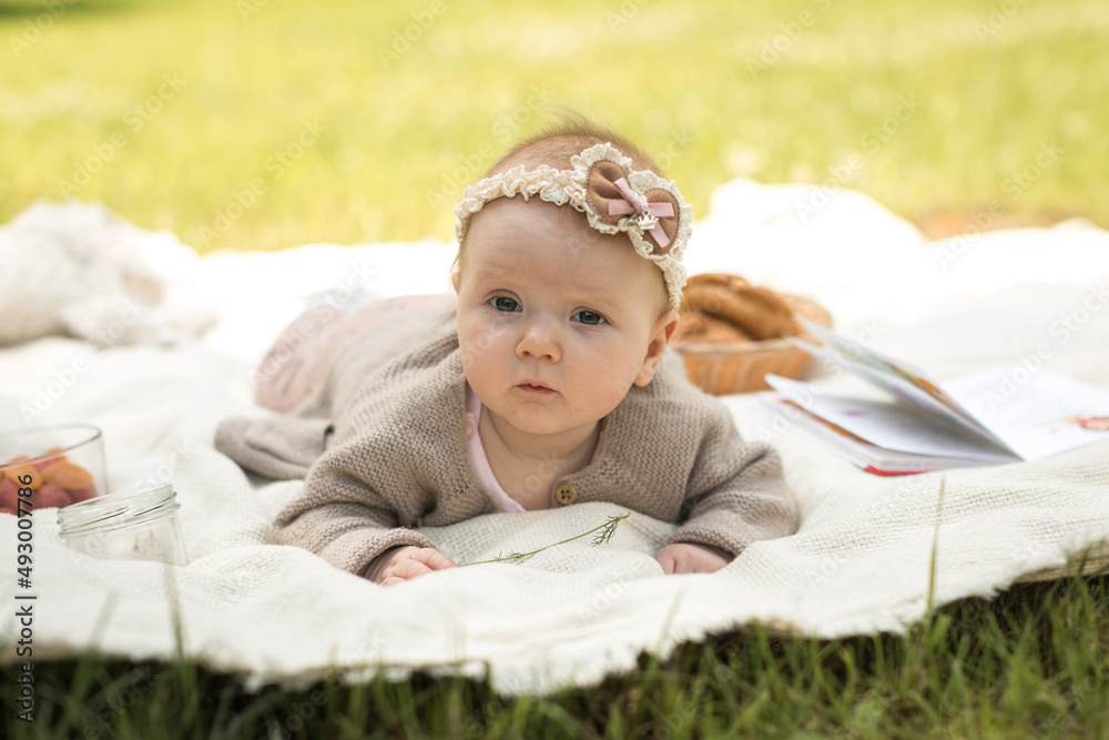 little girl lies on a blanket at a summer picnic