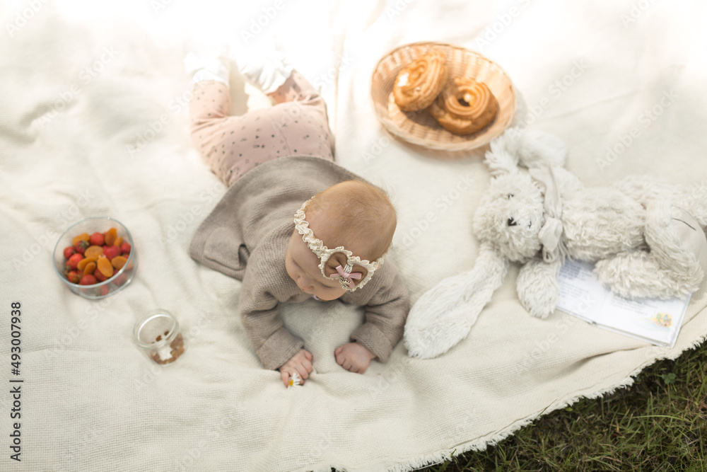 little girl lies on a blanket at a summer picnic