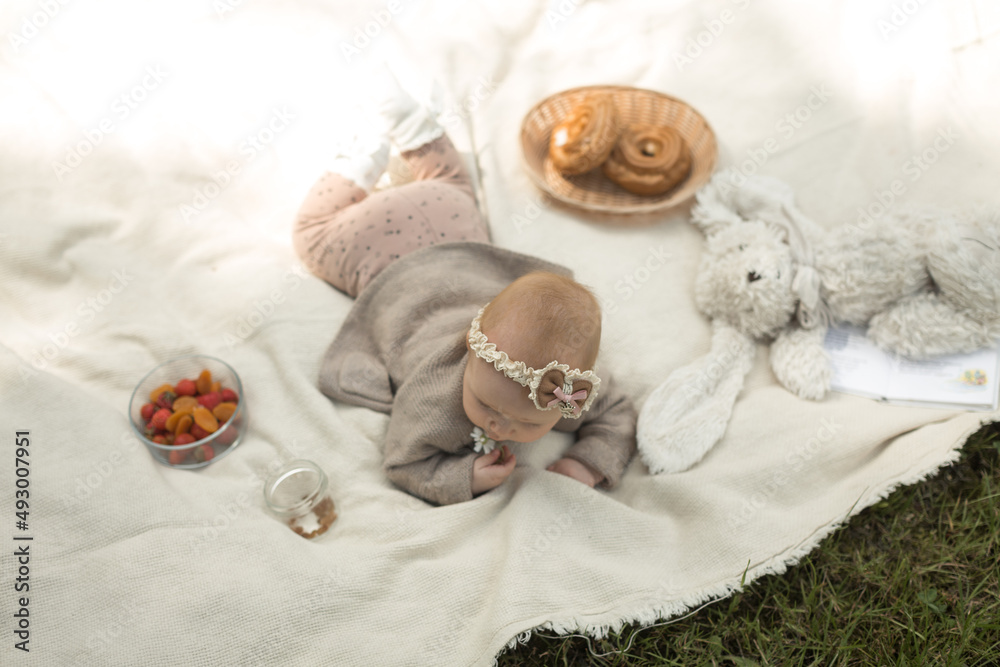 little girl lies on a blanket at a summer picnic