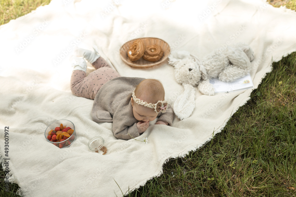 little girl lies on a blanket at a summer picnic
