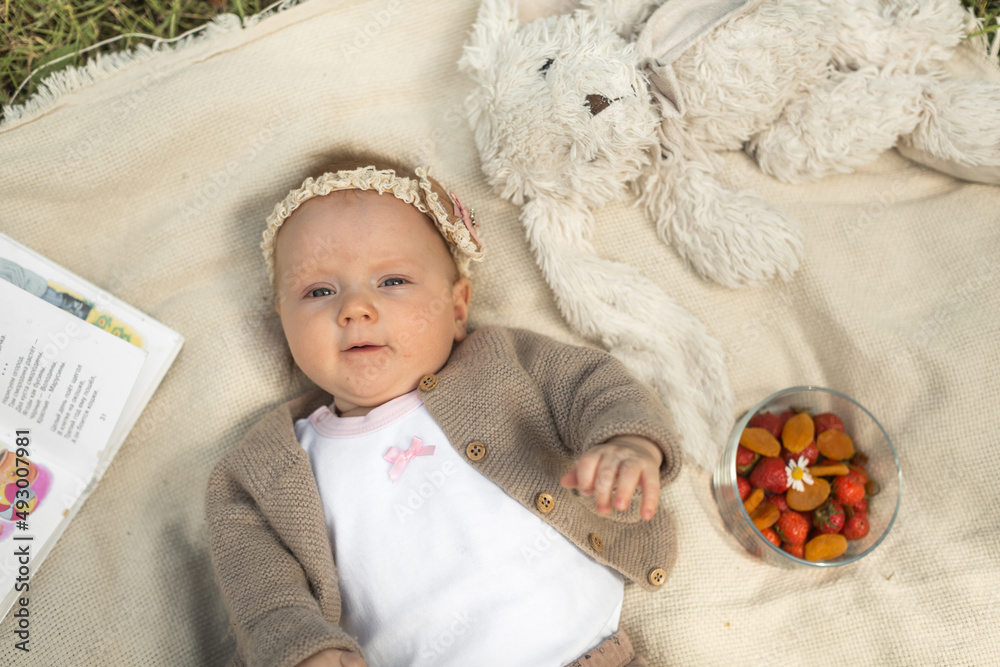little girl lies on a blanket at a summer picnic