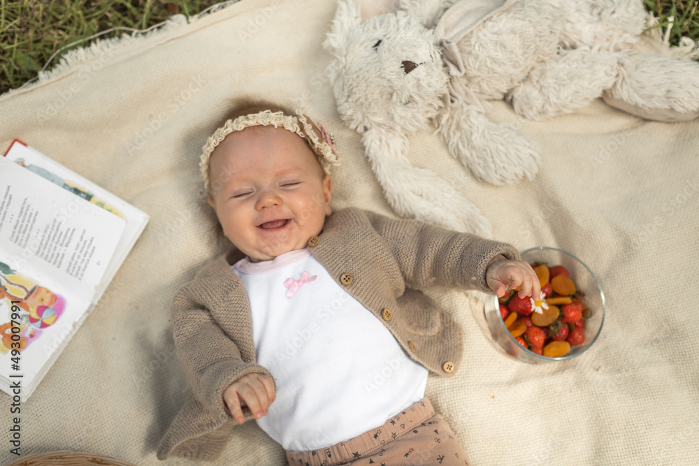 little girl lies on a blanket at a summer picnic