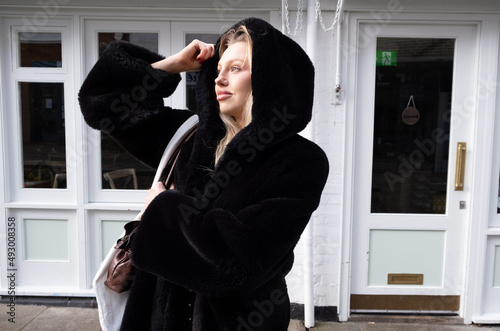 Beautiful Woman with a winter black coat holding the hood