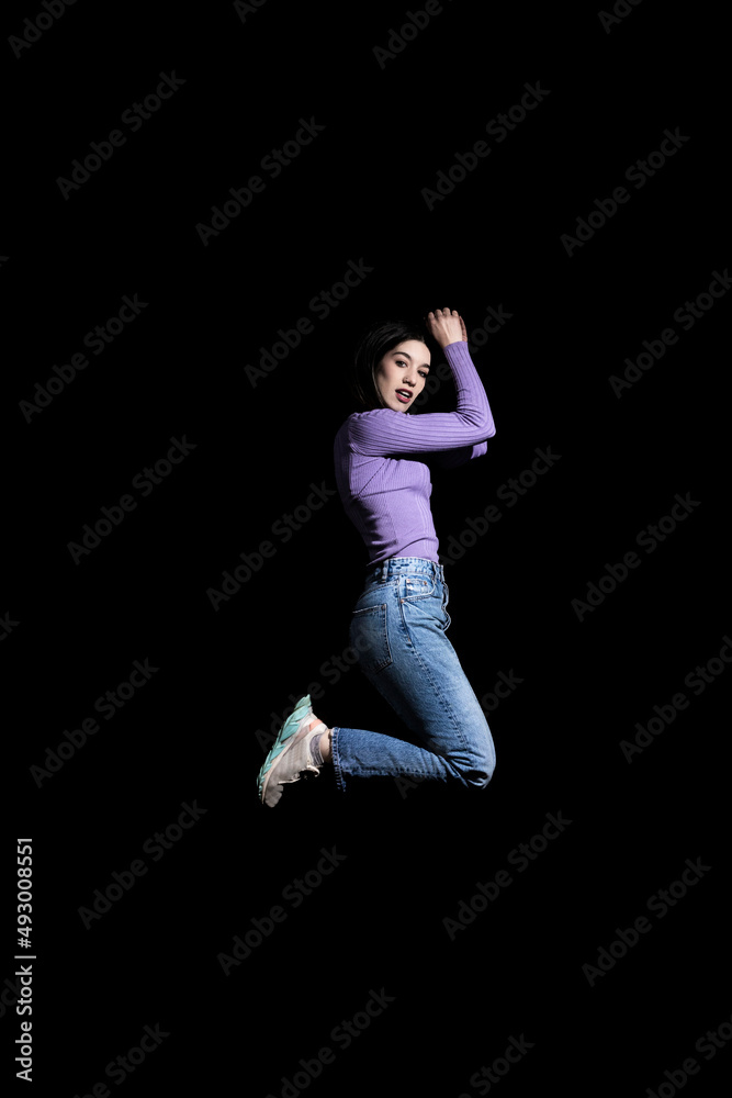 brunette woman jumping on black background