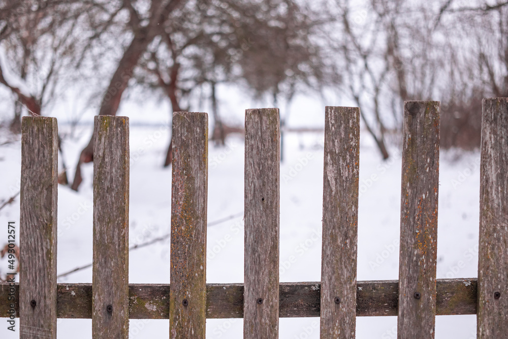 Wooden picket fence with snow in front and behind the barrier