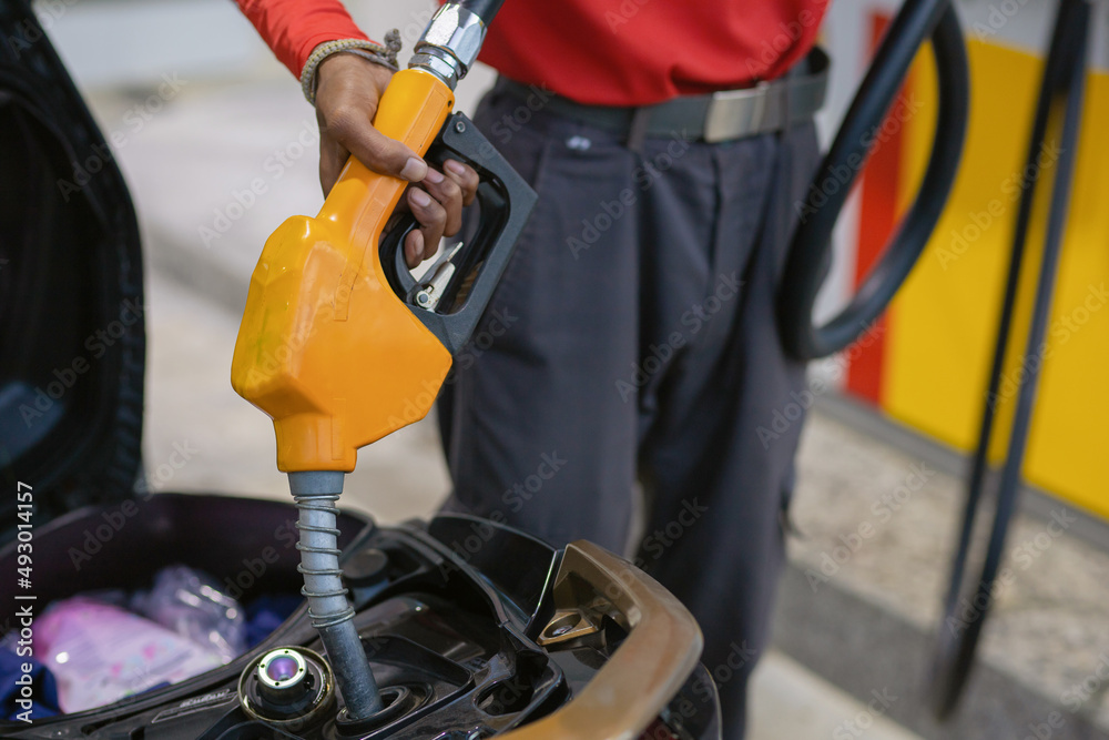 Close up of hand holding nozzle fuel filling oil into motorcycle tank. Transportation and energy concept. Close up of hand holding nozzle fuel filling oil into motorcycle tank. Transportation and energy concept.