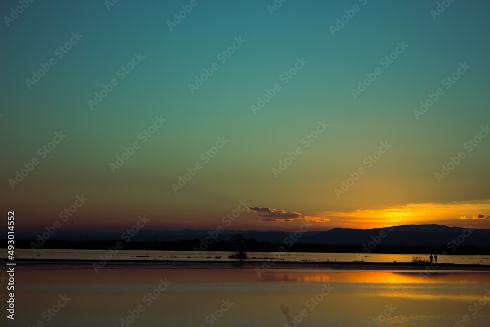 Obraz premium Dos personas a lo lejos contemplando el atardecer.