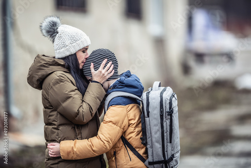 Foto Woman kisses her boy on forehead outdoors as they both stay in the war zone afte