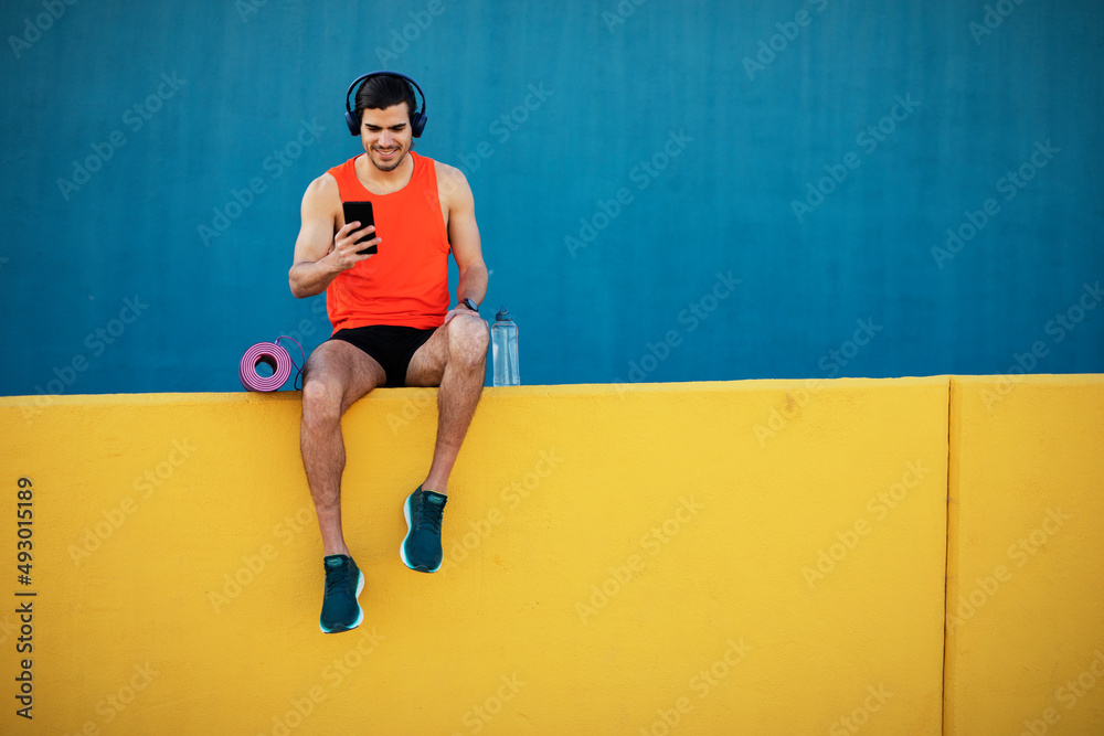 Young sexy man training outside. Fit handsome man listening the music.