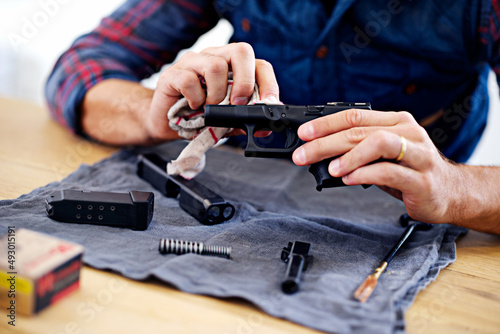 Regular maintenance is essential for every gun owner. Cropped view of a man cleaning his gun. photo