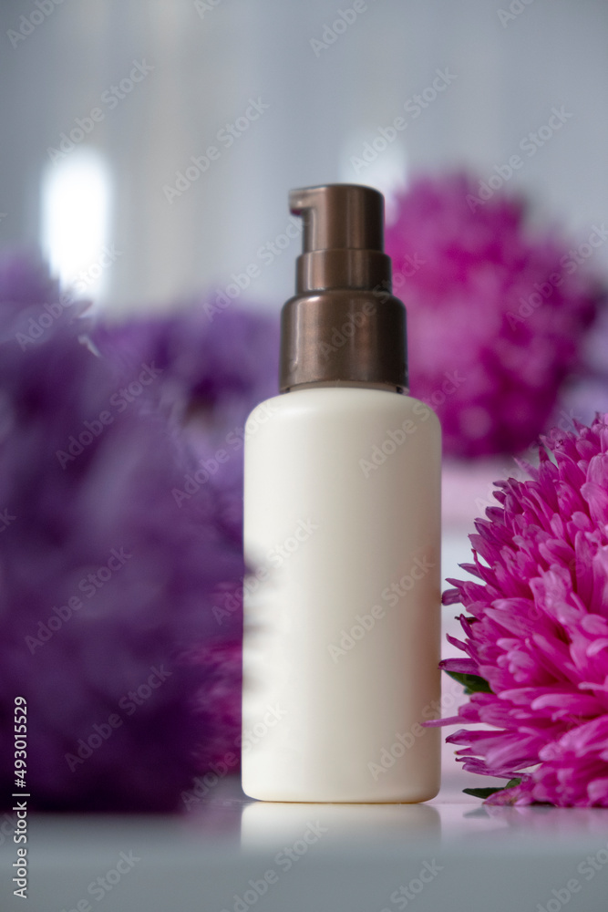 Bottle of beauty product mock up with flowers around, pink purple asters. Face care, anti-aging, exfoliating cosmetic. Organic SPA cosmetics with herbal ingredients. Bottle of beauty product mock up with flowers around, pink purple asters. Face care, anti-aging, exfoliating cosmetic. Organic SPA cosmetics with herbal ingredients.