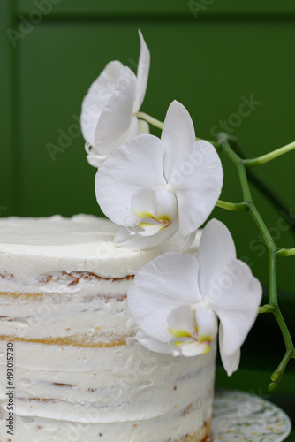 white orchid flowers next to the cake on a green background