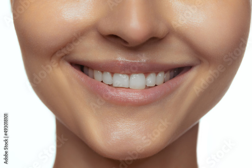 Cropped image of beautiful female lips, teeth, neck and chin isolated over white studio background.