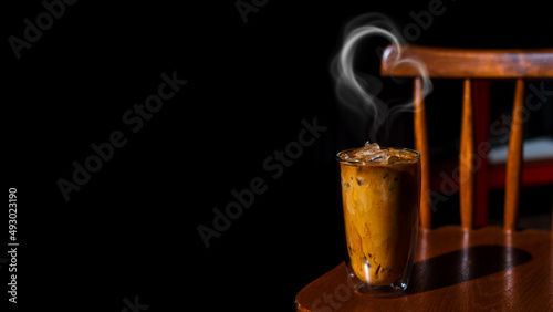 Ice coffee on a wooden table with cream being poured into it showing the texture and refreshing look of the drink