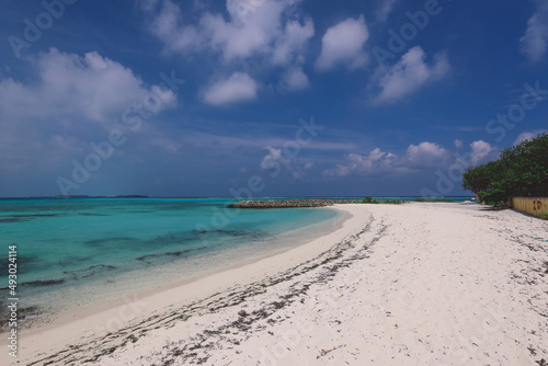 Fototapeta Naklejka Na Ścianę i Meble -  Empty White Sandy Beach with the Palm Trees and Blue Ocean Water on the Paradise Maafushi Island, Maldives