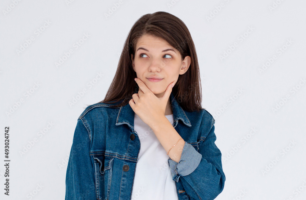 Headshot of cunning beautiful woman with straight dyed hair looking aside holding hand under chin indenting to realize tricky plan. Attractive female having sly expression while looking aside Headshot of cunning beautiful woman with straight dyed hair looking aside holding hand under chin indenting to realize tricky plan. Attractive female having sly expression while looking aside