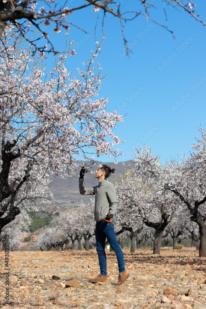 Young man gardener smelling flowers sorrounded by rural landscape