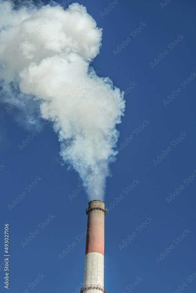 Powerful industrial factory chimney is smoking and polluting the environment with carbon dioxide