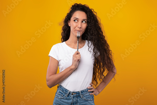 Portrait of Smiling Latin Lady Holding Fork In Mouth photo