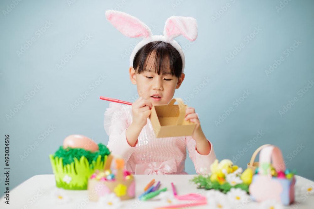 young girl making easter craft against plain background young girl making easter craft against plain background