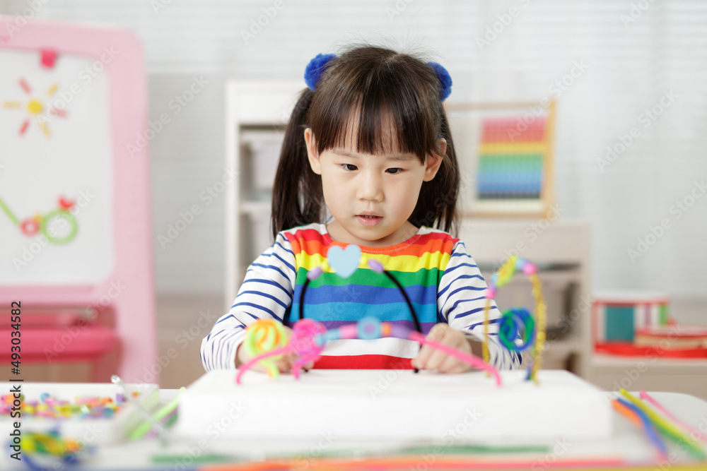 young girl threading beads making craft for home schooling