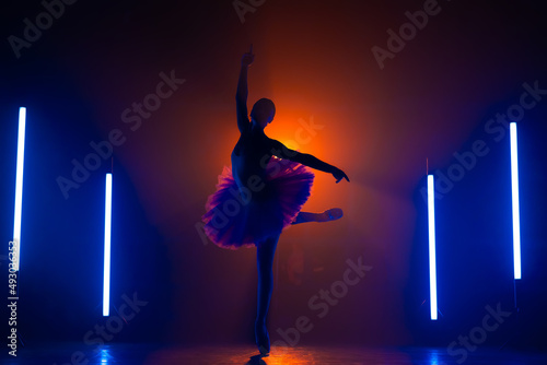 Foto Silhouette of ballerina is practicing elements in studio with neon colorful light