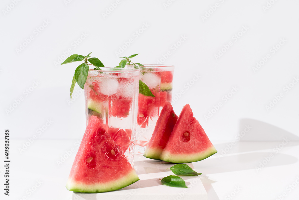 Dos vasos de zumo de sandía con trozos de sandia y hielo sobre fondo claro Dos vasos de zumo de sandía con trozos de sandia y hielo sobre fondo claro