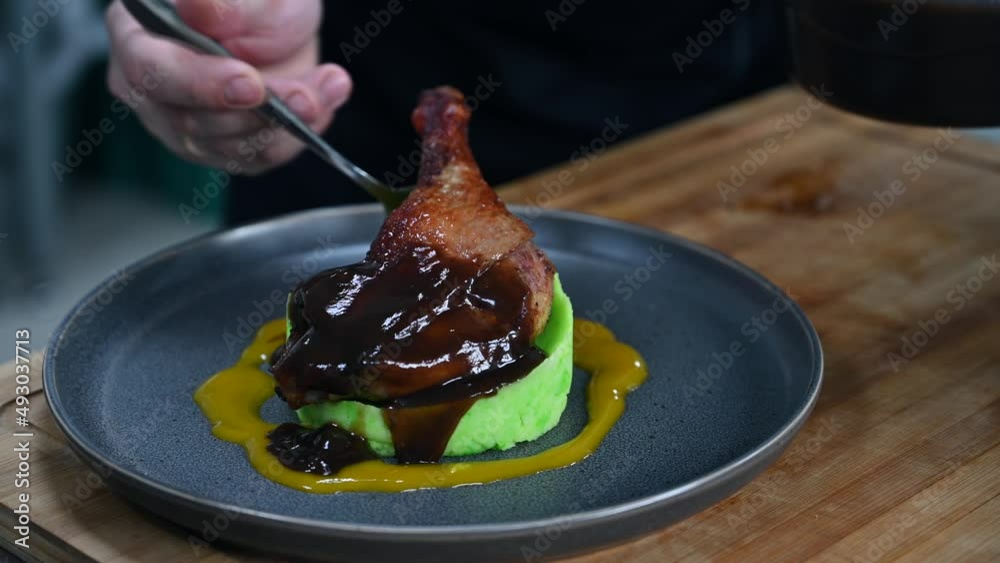 Chef prepares duck legs with green pea puree at the restaurant kitchen