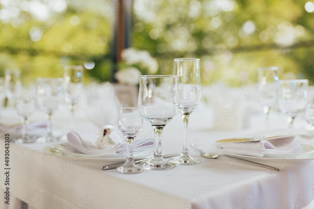 Closeup shot of a restaurant table with empty glasses and a plates with a napkin on top. Beautiful table setting for wedding or dinner. Closeup shot of a restaurant table with empty glasses and a plates with a napkin on top. Beautiful table setting for wedding or dinner.