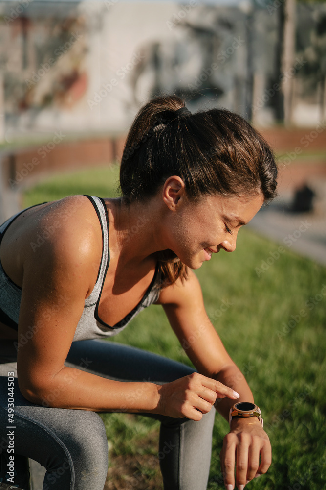 Fit athlete woman in sportswear outdoors. Young woman resting after training Fit athlete woman in sportswear outdoors. Young woman resting after training