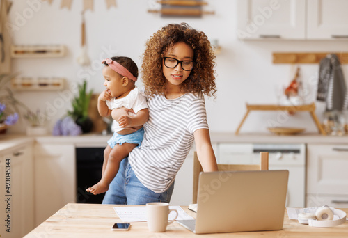 Multitasking african american self-employed mother working with baby from home on maternity leave photo