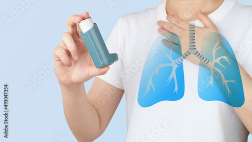Young woman using blue asthma inhaler for relief asthma attack. Pharmaceutical products is used to prevent and treat wheezing and shortness of breath caused asthma or COPD. Lung organ anatomy. photo