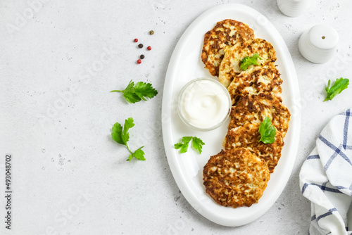 Broccoli chicken fritters on white dish with sour cream sauce. Top view, space for text.