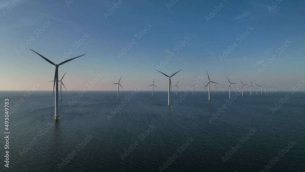 Wind turbines producing sustainable renewable energy in an offshore wind parkt. Drone point of view.
