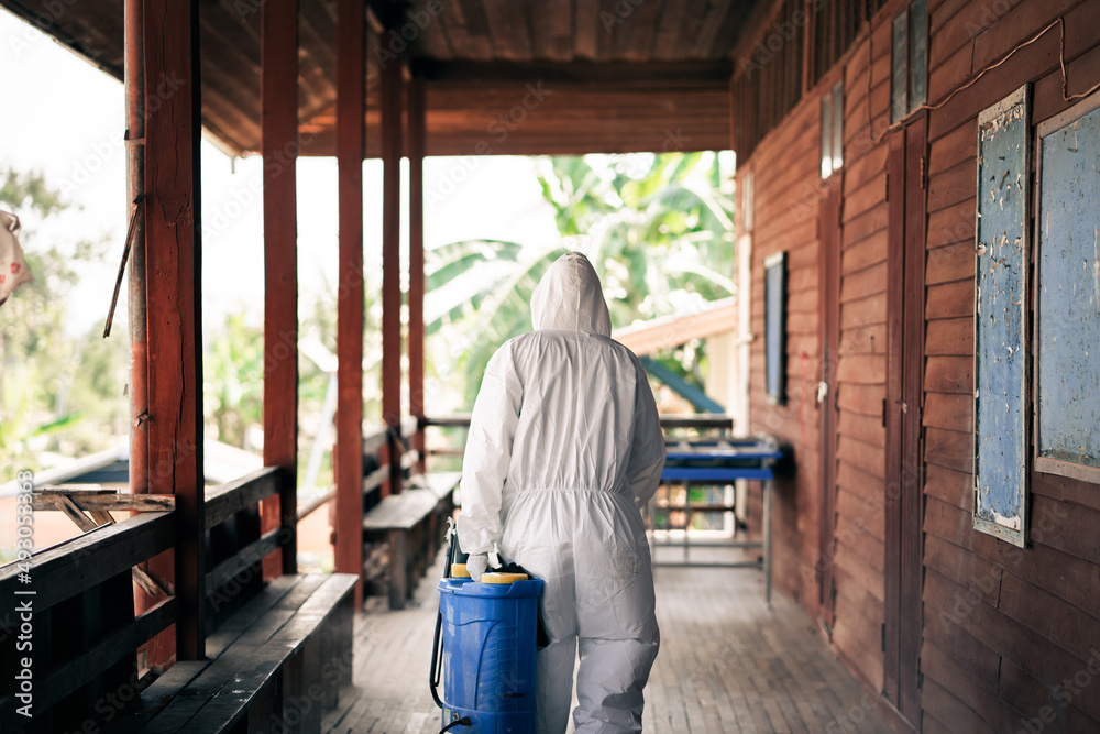 A man wearing protective suits masks and disinfectant tank spray.Big cleaning and disinfection of school amid coronavirus outbreak, infection prevention, and an epidemic of covid-19 control.