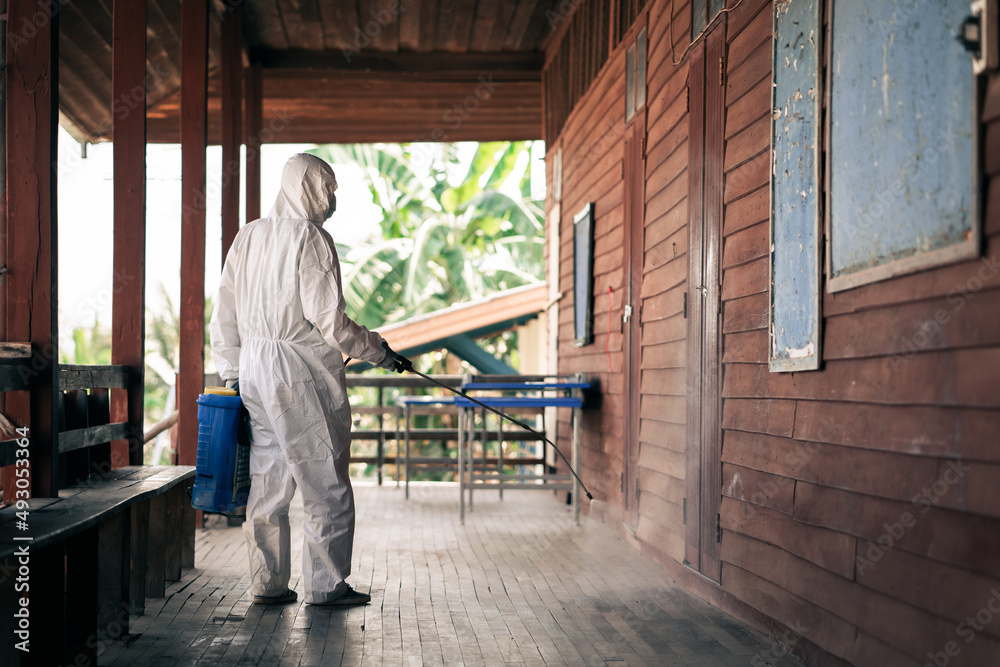 A man wearing protective suits masks and disinfectant tank spray.Big cleaning and disinfection of school amid coronavirus outbreak, infection prevention, and an epidemic of covid-19 control.