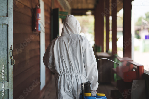 A man wearing protective suits masks and disinfectant tank spray.Big cleaning and disinfection of school amid coronavirus outbreak, infection prevention, and an epidemic of covid-19 control.