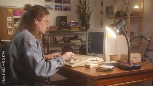 Young woman typing commands in a vintage computer of late 80s in her bedroom.