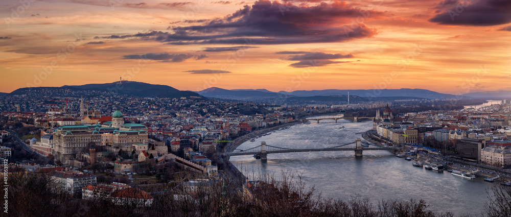 Elevated panoramic skyline view of Budapest, Hungary, at sunset with Buda Castle Royal Palace, Szechenyi Chain Bridge, Parliament, Matthias Church at the Danube river