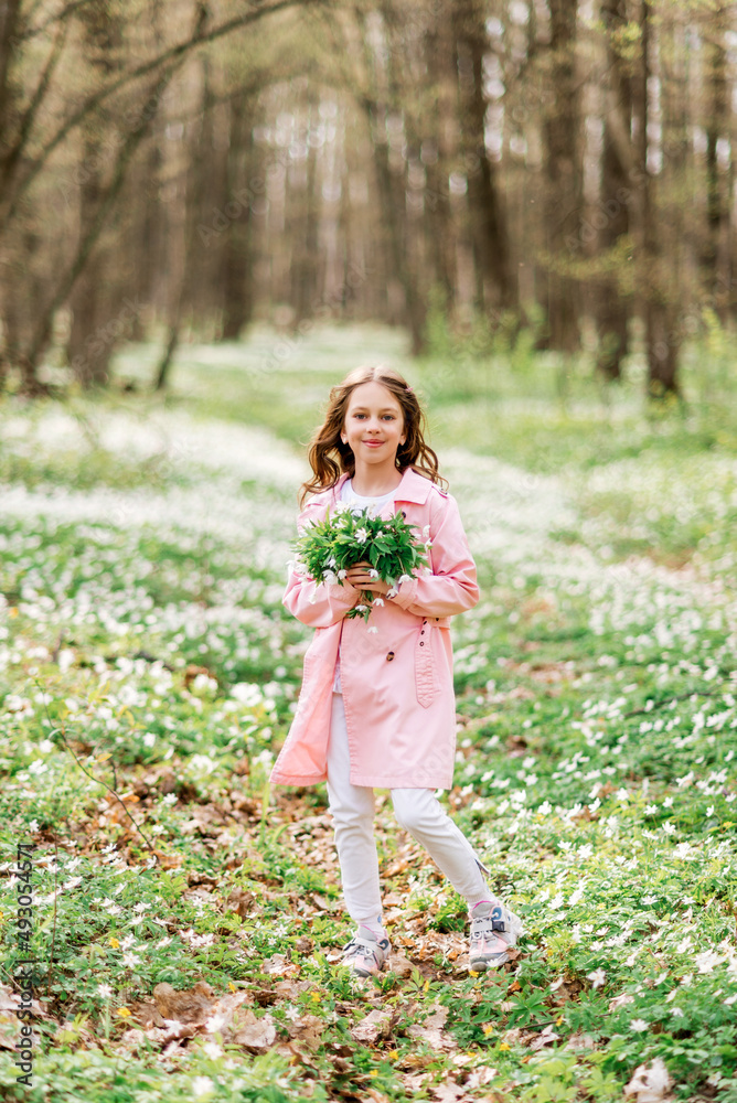 cute girl with a bouquet of primroses in the spring forest. A child on a walk in the park cute girl with a bouquet of primroses in the spring forest. A child on a walk in the park