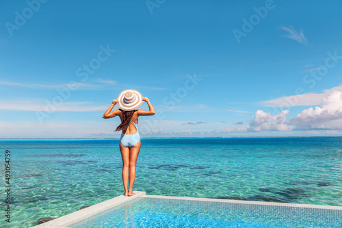 Luxury vacation hotel in Tahiti woman relaxing at infinity pool looking over ocean in French Polynesia travel summer holiday.
